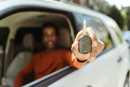 selective-focus-closeup-african-american-man-sitting-in-car-behind-wheel-showing-car-key-1536x1024